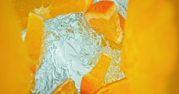 Super slow motion 1000fps video of fresh orange slices falling into rippling water, creating a sparkling splash, perfect for drink, cocktail, beverage and summer visuals.