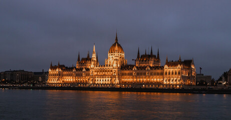 Fototapeta premium View from Buda Embankment of the Parliament building illuminated by floodlights on Pest embankment in Budapest in Hungary