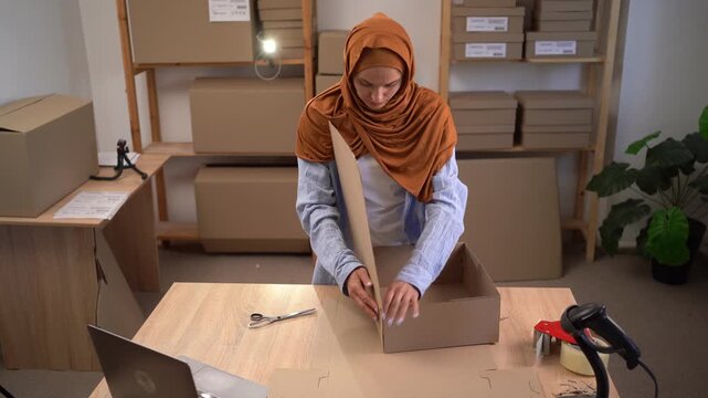 Muslim woman assembling Cardboard box for shipping orders. Working in small home office