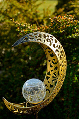 lampa ogrodowa z metalu w kształcie księżyca z ze świecącą, szklaną kulą po środku, a moon-shaped metal garden lamp with a luminous glass ball in the center © kateej