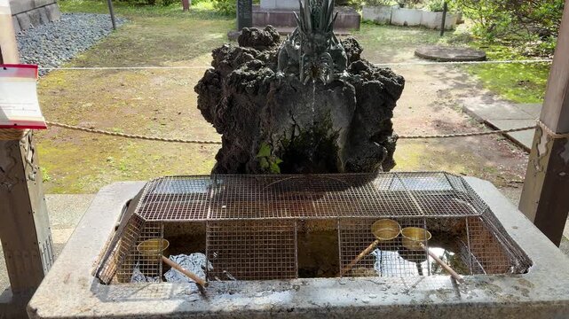 Traditional Japanese chozuya water purification pavilion at a temple in Tokyo. Bronze dragon fountain slowly pours fresh water into a stone basin. 