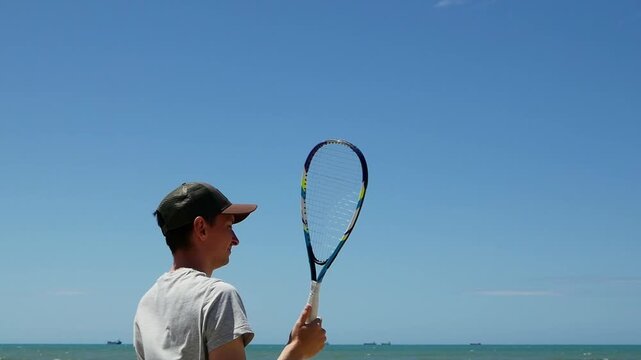 Man returning shuttlecock in speed badminton on sandy beach , summer fun, outdoor game, active lifestyle, beach vacation.