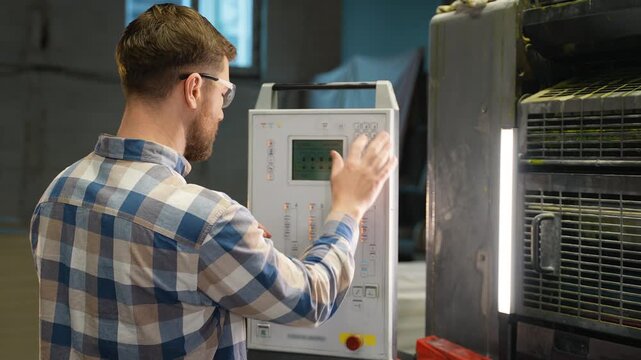 Printing house worker operating industrial press machine