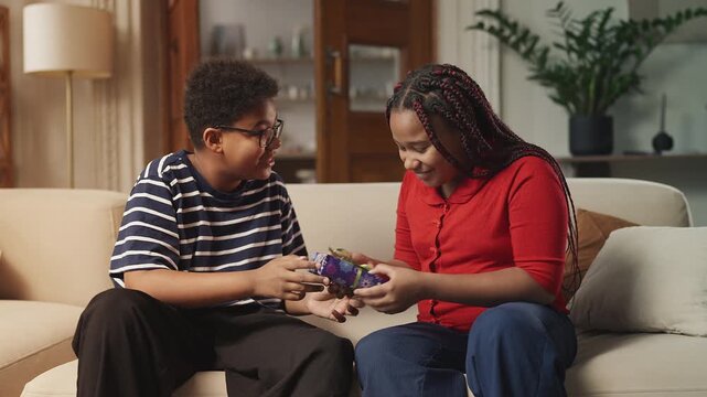 African American teen boy giving birthday present to his girl pal, warm hug