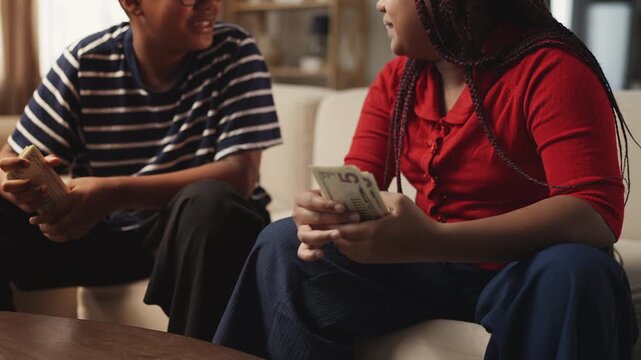 Siblings counting dollar bills and high-fiving each other, young entrepreneurs