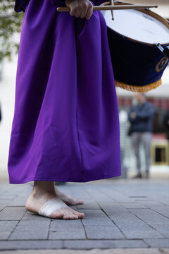 Close-up of a barefoot penitent with bandaged feet playing a drum during a Holy Week procession in  Avil&eacute;s, Asturias.