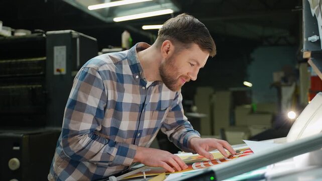 Professional graphic designer checking print quality at factory