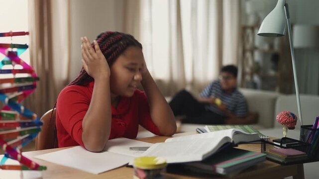 Sister trying to study while her brother loudly plays video games nearby