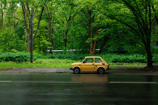 Vintage yellow Fiat 126p Maluch parked on a rainy street in Wroclaw, Poland