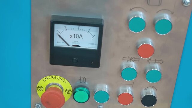 Machine control panel with many buttons, ammeter and an emergency stop button. Closeup. Shot in motion