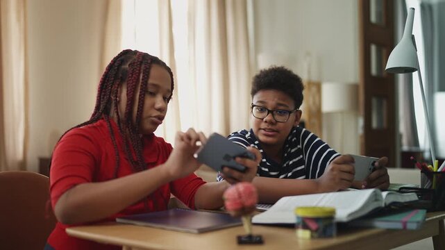 African American children playing on smartphones instead of studying at home