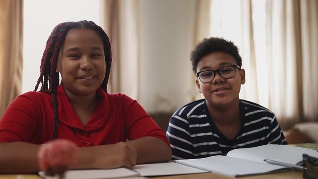 POV of two diligent African American siblings attending online lesson at home