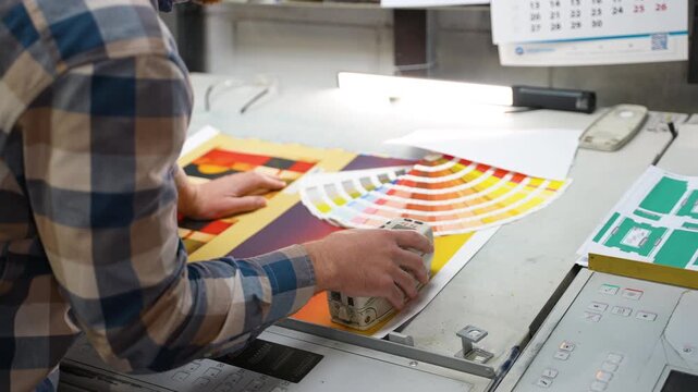 Graphic designer checking color proofing with a spectrophotometer