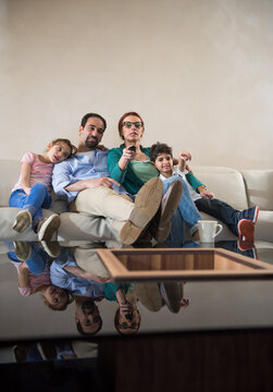 Modern Middle Eastern Arab family relaxing on couch watching TV together in cozy living room