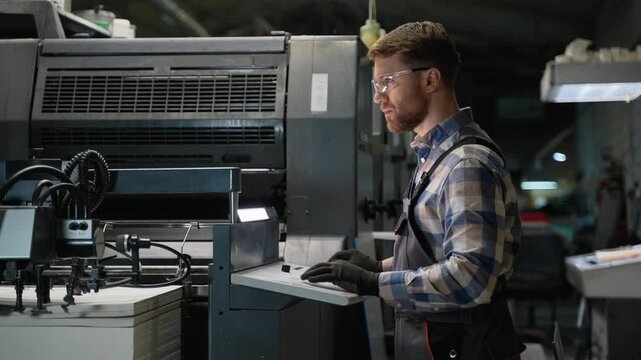 Professional printing machine operator working at print plant