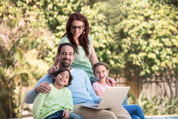 Fototapeta premium Modern Middle Eastern Arab family enjoying time together outdoors with laptop and laughter