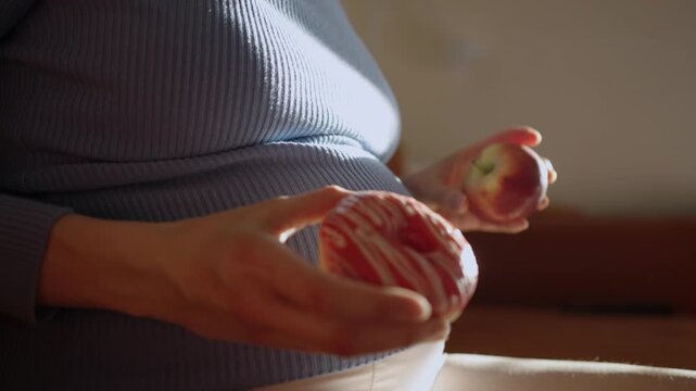 Pregnant woman facing a difficult choice between a healthy red apple and a sugary pink donut, ultimately selecting the fruit, symbolizing healthy eating and diet during gestation