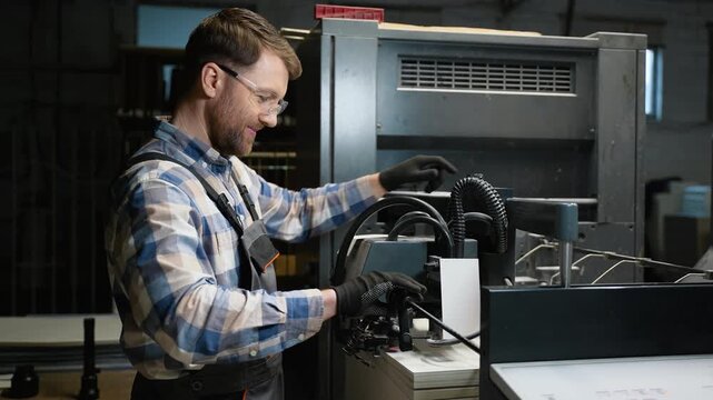 Print plant operator adjusting industrial printing machine