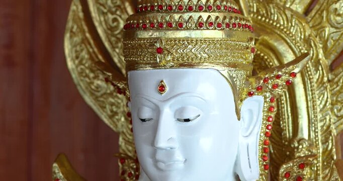 White Buddha statue with golden ornaments in a Thai temple, symbolizing peace, faith, spirituality, sacred art, and Buddhist culture