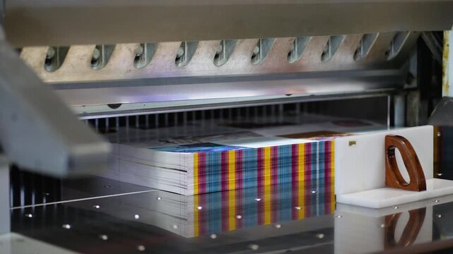 Industrial guillotine machine cutting paper stack in a printing factory