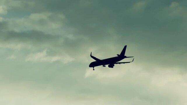 Commercial passenger airplane landing with gear down in cloudy overcast sky. Silhouette of twin-engine jet airliner flight in foggy weather, aviation transport and tourism travel background.