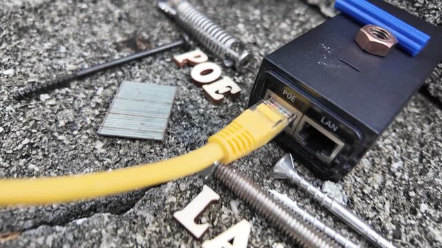 Wooden letters spelling 'POE' are placed near a coiled spring and a network device.
