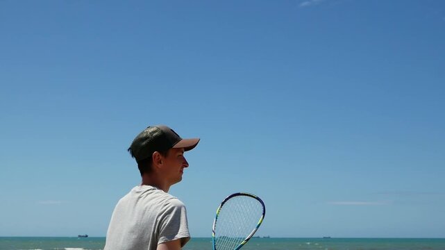 Man returning shuttlecock in speed badminton on sandy beach, athletic training, fast-paced outdoor sports, active lifestyle.