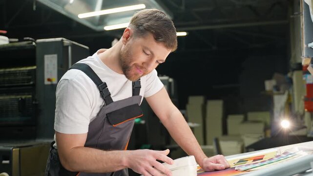 Printing house worker checking color on proof sheet