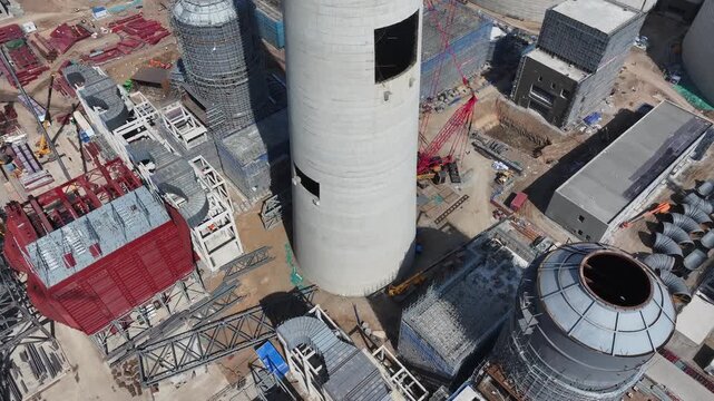 Aerial view of large industrial chimney construction site with cranes and steel frameworks