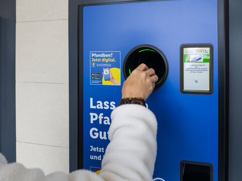 15 May 2026, Aachen, Germany. Close-up of hand inserting plastic bottle into digital reverse vending machine for deposit return system
