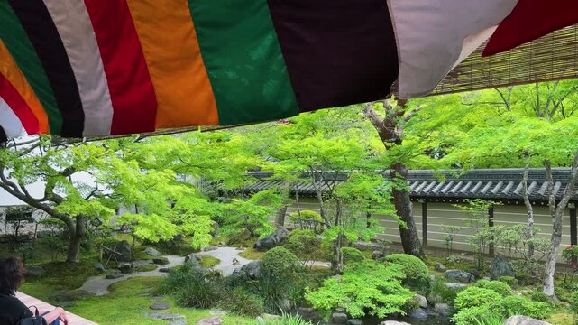 Traditional Zen garden at Eikan-do Zenrin-ji Temple in Kyoto, Japan. Fresh green maple trees surround the calm courtyard during a sunny spring day in April. Five-colored Buddhist banners.
