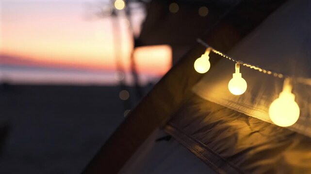 Camping tent illuminated with decorative string lights during peaceful beach evening.