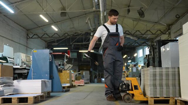 Printing plant worker moving paper stack with pallet jack