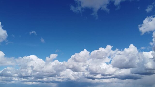 4K aerial drone view of a vast blue sky framed by white fluffy clouds, cinematic background with central copy space for text, peaceful sunny day atmosphere, high altitude cloudscape, UHD footage