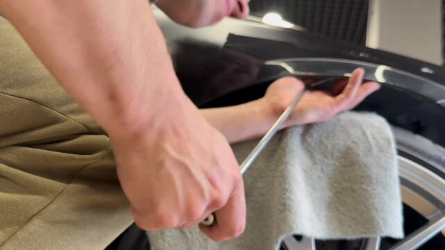 PDR. Process of paintless dent repair on car body. The mechanic at the auto shop with tools to repair dents in car body. Body repair. A specialist repairs a dent on the car body without painting. PDR.