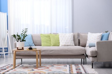 Fototapeta premium Soft colorful pillows on gray sofa indoors