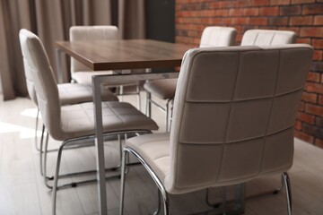 Fototapeta premium Stylish comfortable chairs and wooden table in office, closeup