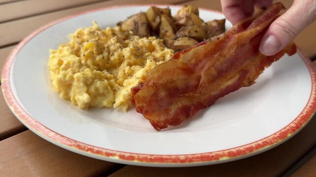 Eating a Slice of Bacon on a Breakfast Plate