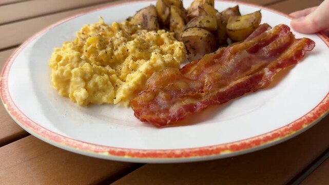 Serving a Plate of Scrambled Eggs, Bacon and Fried Potatoes