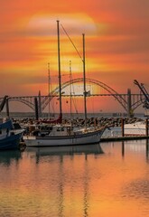Fototapeta premium Commercial fishing boats reflected in Newport bay at sunset with Yaquina Bay Bridge in the background on a calm day