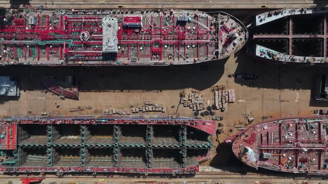 Aerial view of four ships under construction in a dry dock shipyard