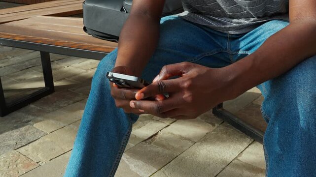 Watching a phone screen while sitting on a stone patio in the afternoon