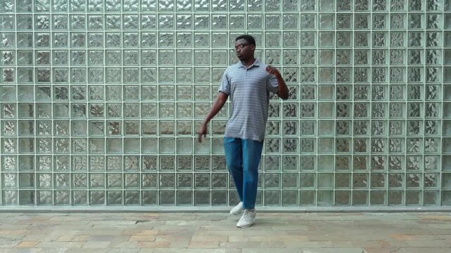 Dancer practices steps in front of glass wall during afternoon in urban location