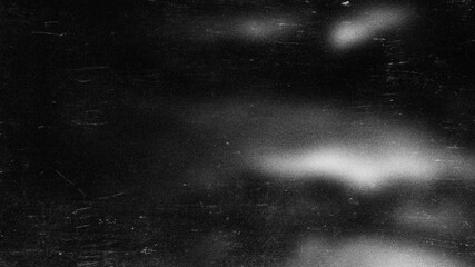 Fototapeta premium Abstract grainy monochrome background with light spots and scratch marks on black for banner.