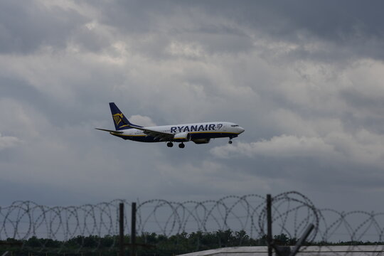 Ferno, Italy - May 15, 2026: Passenger airplane taxiing at Milan Malpensa Airport with control tower and runway under cloudy sky