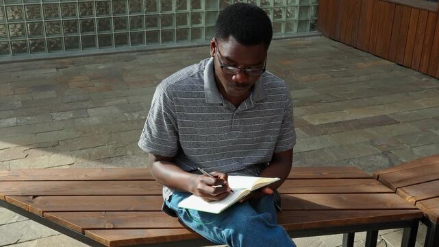 Man sits on bench and reads a book in a modern area during the afternoon