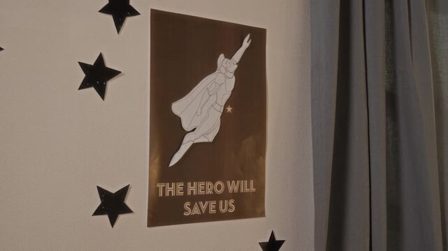Close-up of handmade poster with popular comic action hero flying through air, dressed in costume and cape, hanging on wall in child bedroom, representing role model, dream and inspiration