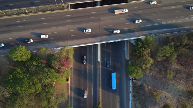 Top down drone footage of multilane freeway traffic and bridge structures in Centro Sur Queretaro, Mexico, with cinematic evening shadows and urban mobility concept