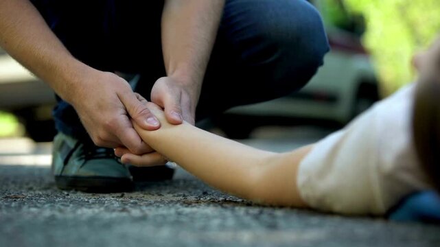 Paramedic Checking Pulse of Unconscious Person on the Ground with Ambulance in Background