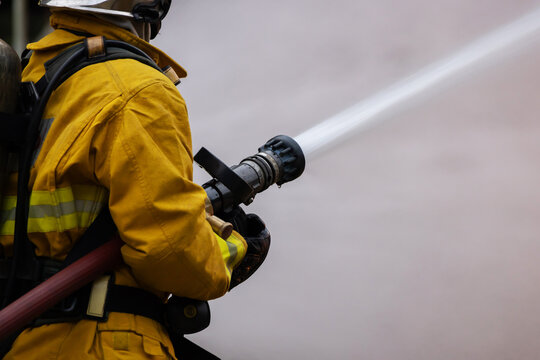 Firefighter use a water hose to extinguishing fire